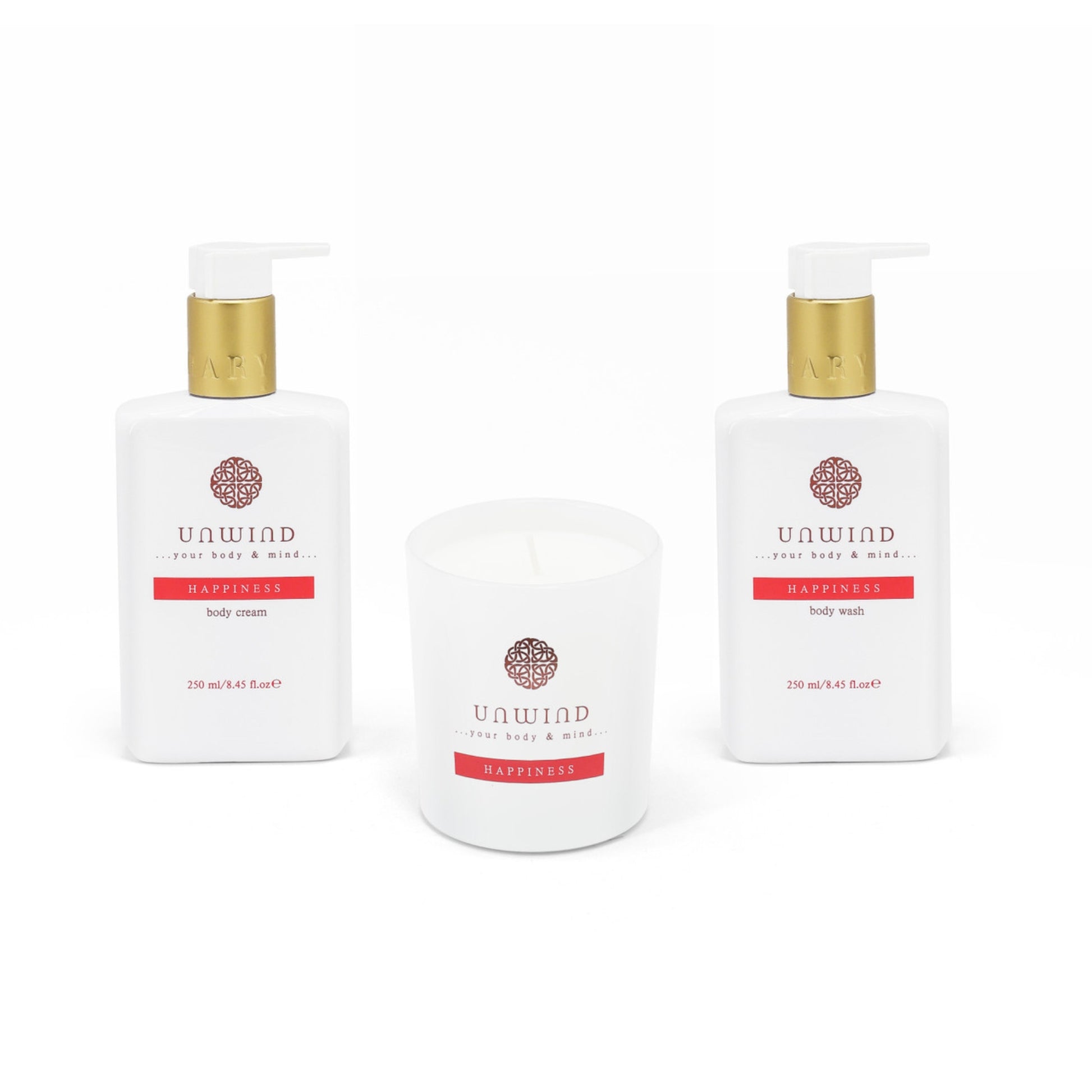 Two bottles of Unwind Happiness body wash, body cream and a candle on a white background