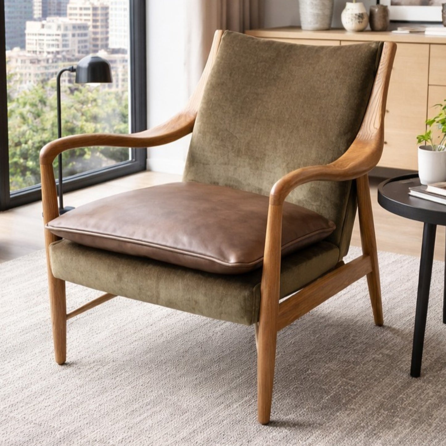 Brown armchair with wooden frame in a room with large windows and decor.