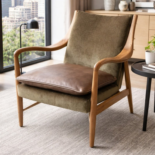 Brown armchair with wooden frame in a room with large windows and decor.