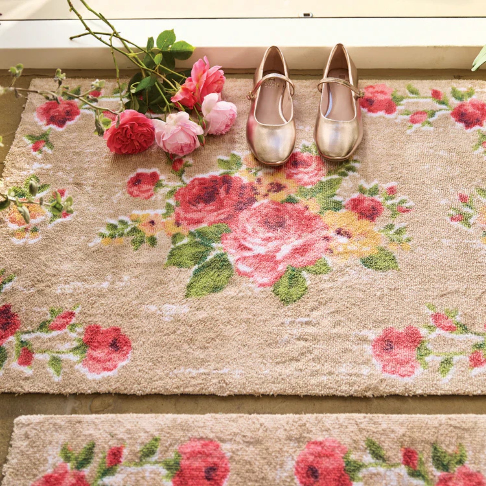 Floral-patterned doormat with shoes and flowers on a wooden floor