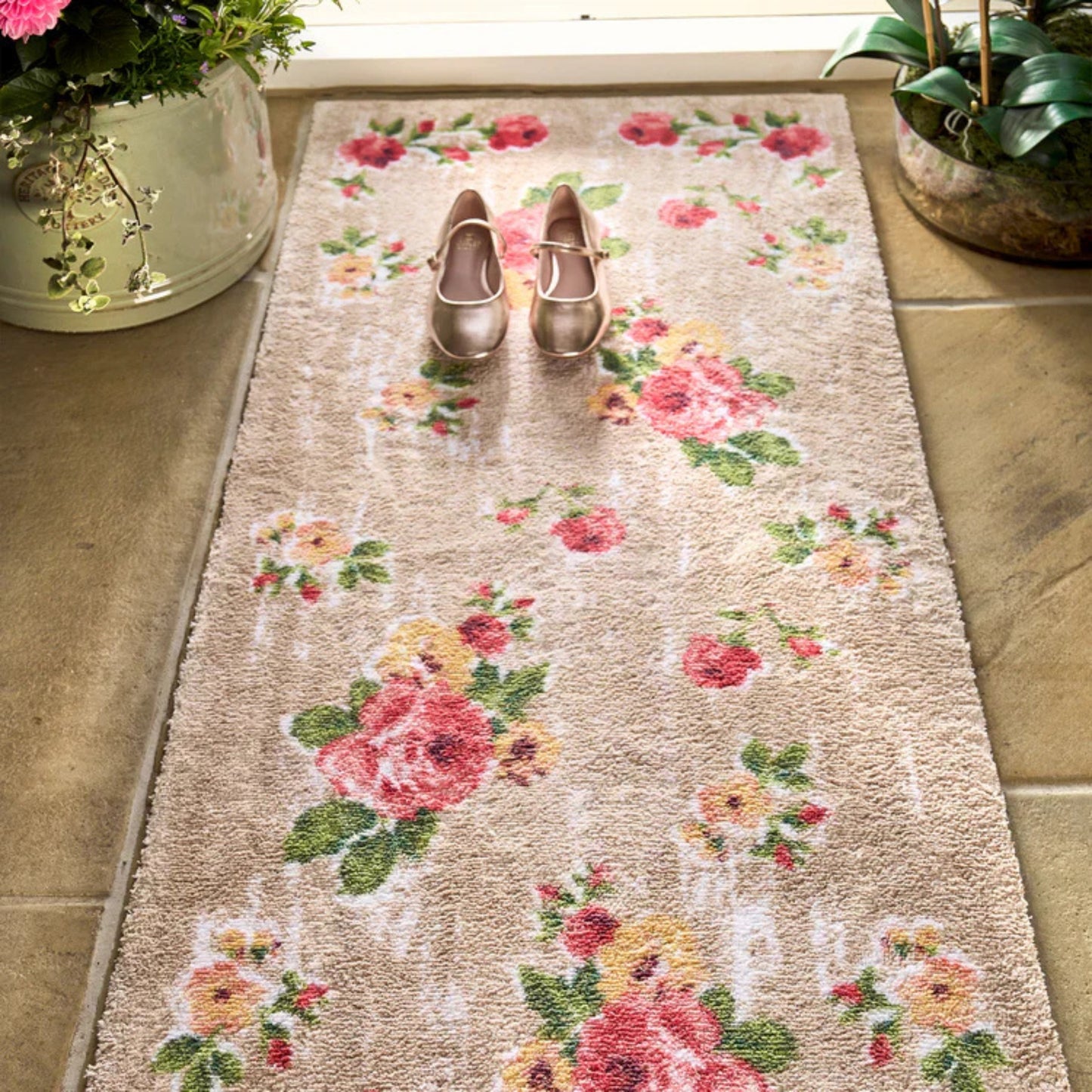 Floral patterned rug with two shoes on a tiled floor.