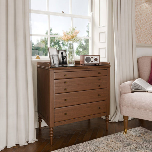 Wooden dresser with decorative items in a room with a window and chair.